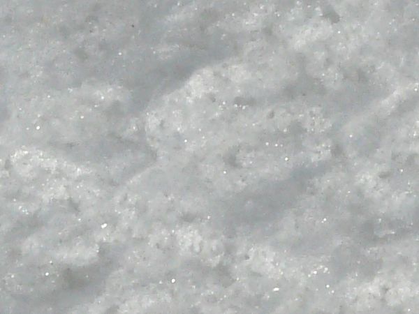 Rough ice texture, made up of bright white snow and dark, reflective chunks of ice.